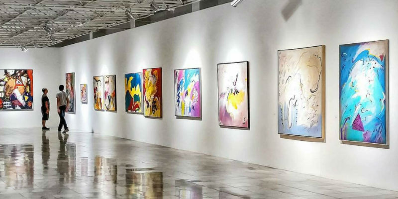 Paintings hanging on a wall in an art gallery. Photo by Matheus Viana.