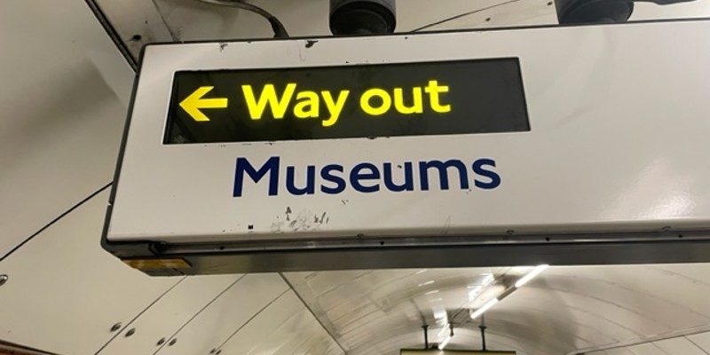 Sign in the London Underground with the words way out next to an arrow with the word museum underneath