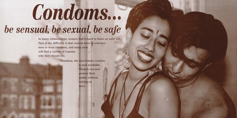 An Asian couple embrace by a window; advertisement for the new female condom by the Black HIV/AIDS Network.