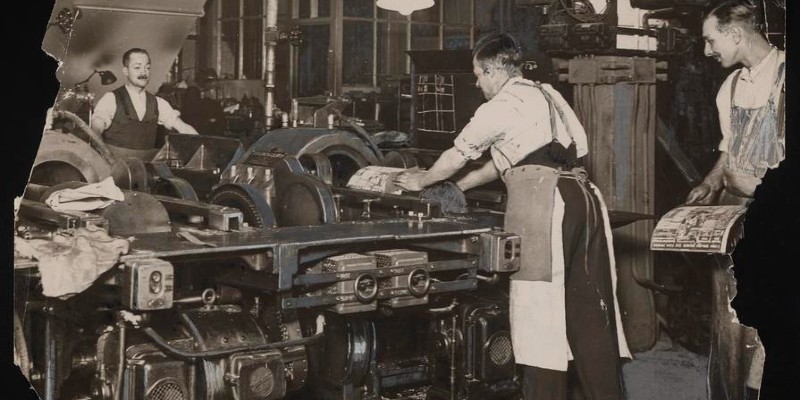 Photograph of workers setting up machinery to print a newspaper